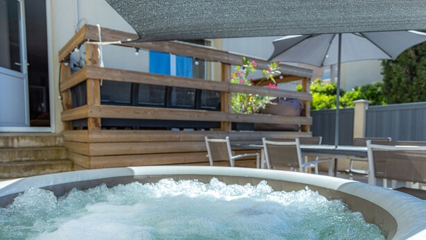 A hot tub with a wooden deck and outdoor furniture. - IDEALLY LOCATED GD APARTMENT, PARKING & PRIVATE TERRACE, JACCUZI, QUIET, DOMLOC (Carcassonne)