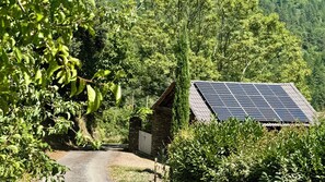 Entorno rural con un edificio de piedra y un panel solar.