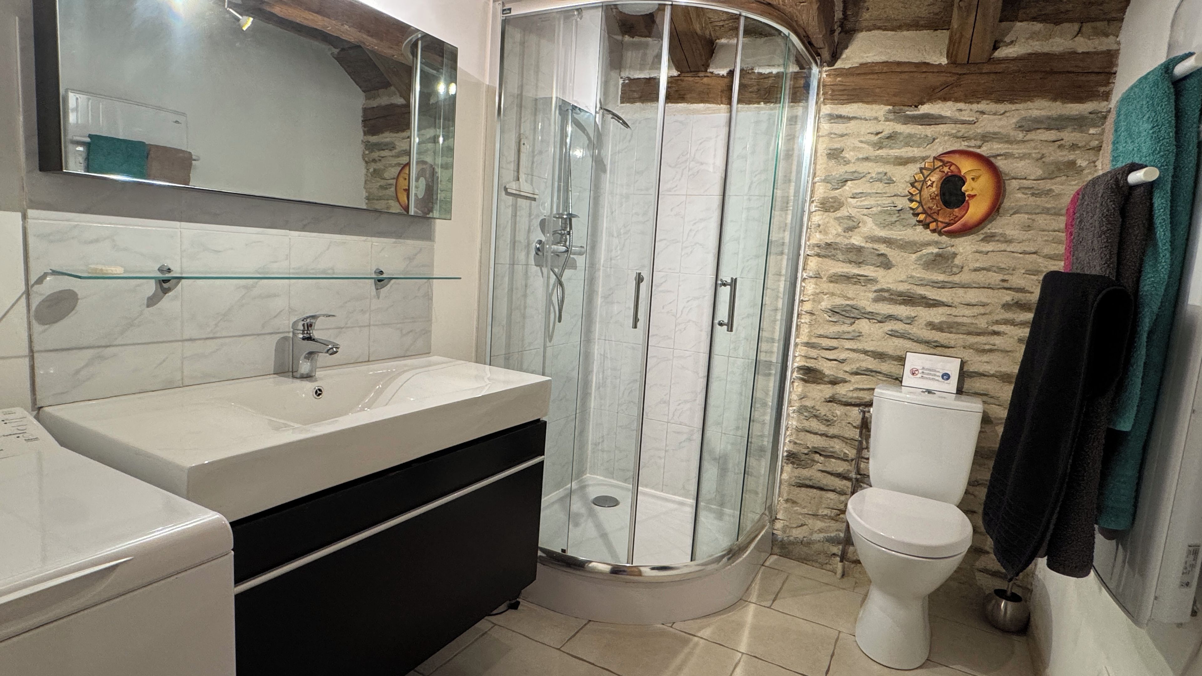 Een badkamer met een douchecabine, een wit wastafelmeubel en een toilet.