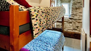 Una cama individual en literas con una colcha y almohada a lunares.