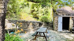 A stone wall, a wooden bench, and a small building with a door. - CASTAGNERE 4* IN THE CÉVENNES: Vacation Rental in Aujac in the Cévennes National Park (Aujac)