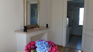 A dining area with a table, a vase of flowers, a mirror, and a doorway leading to another room. - French Charm.  Charming 40-square-meter apartment.⭐️⭐️⭐️ (Honfleur)