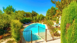 A swimming pool with a metal fence, surrounded by lush greenery and a clear blue sky. - Air-conditioned villa with private pool 5km from Avignon center (Avignon)
