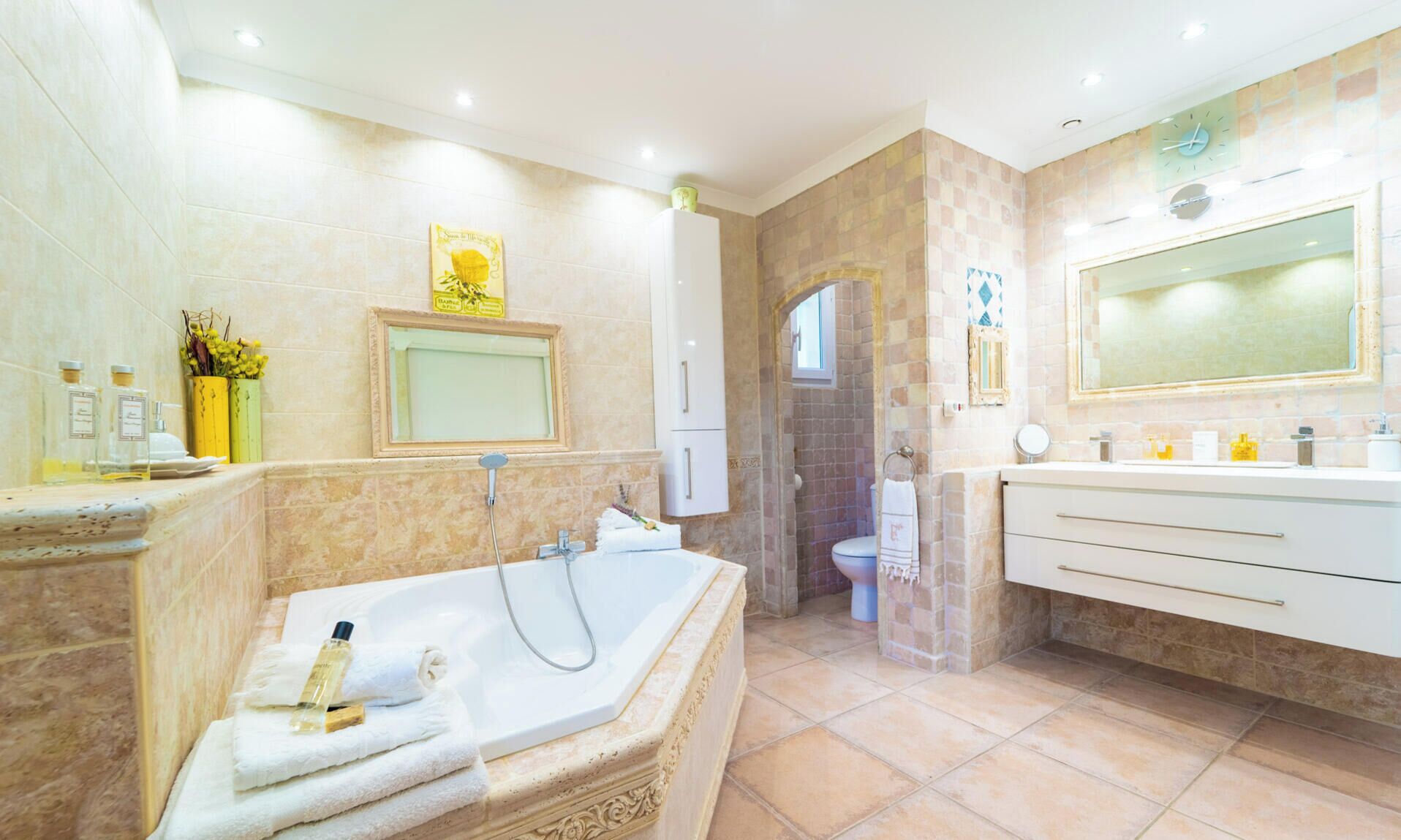 Un bany modern amb una banyera independent, un mirall gran i una zona de lavabo separada.