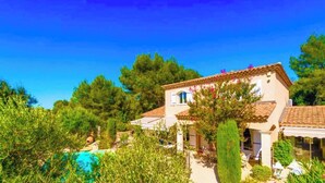 Una villa con piscina, rodeada de exuberante vegetación y árboles.