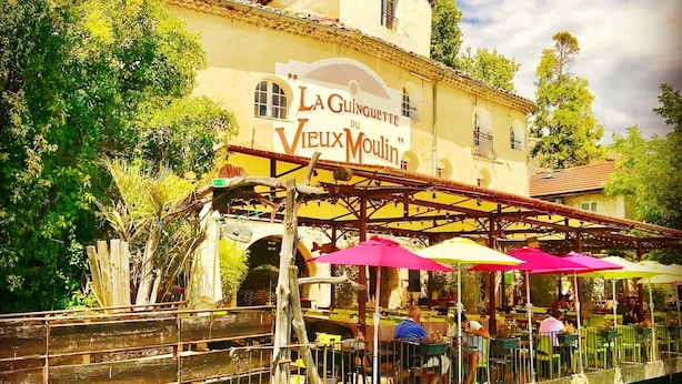 Un restaurante a orillas del río con terraza y un letrero que dice "La Guinguette du Vieux Moulin".