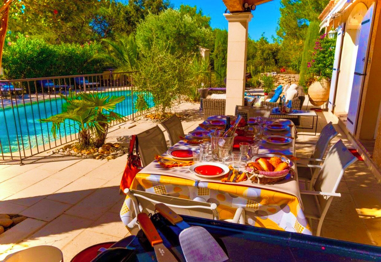Zona pranzo all'aperto con piscina sullo sfondo.