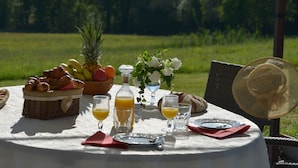 A table set outdoors with a basket of croissants, fruits, and juice glasses.