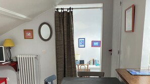 Ruokailutila, jossa on pöytä ja tuolit, patteri, lamppu ja seinällä olevia tauluja.