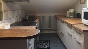Kompakti keittiö, jossa on kaasuliesi, kahvinkeitin ja mikroaaltouuni.