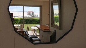 A room with a large octagonal mirror on the wall, a dining area with a table and chairs, and a view of the sea through large windows. - Beautiful VILLA 100m2 with view and direct access to the sea, 3 bedrooms, bathroom, living room, in enclosed park (Fouras)