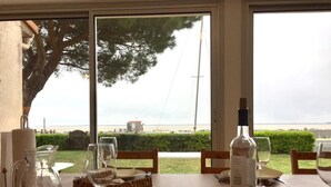 A table set for dining with a view of the sea, a bottle of wine, and a pitcher. - Beautiful VILLA 100m2 with view and direct access to the sea, 3 bedrooms, bathroom, living room, in enclosed park (Fouras)