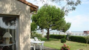 A patio with a table and chairs, a lamp, a coffee pot, and a view of the sea. - Beautiful VILLA 100m2 with view and direct access to the sea, 3 bedrooms, bathroom, living room, in enclosed park (Fouras)