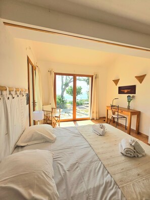 Une chambre à coucher comprenant un lit, un bureau, une chaise et donnant sur l’extérieur.