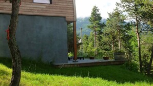 Un bâtiment moderne en bois, doté d’une grande fenêtre et entouré d’une végétation luxuriante et d’arbres.