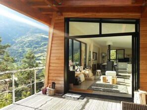 Ein modernes Interieur mit Holzfassade, großen Glasfenstern und Blick auf eine gebirgige Landschaft.