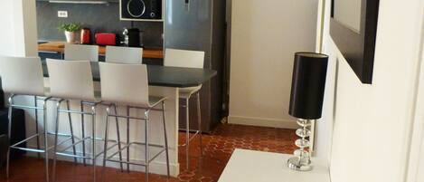 A modern kitchen with grey cabinets, a white dining table with four chairs, and a black floor lamp.