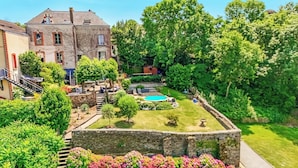 A courtyard with a swimming pool, stone walls, and lush greenery.