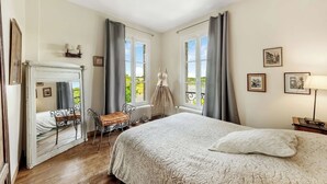 A bedroom with a bed, a chair, a dresser, and a view of the outdoors. - Waterfront Family Home | Pool, Spa & Fitness (Ombrée D'anjou)