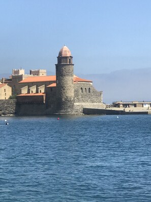 Ein historisches Steinhaus mit einem Turm, am Ufer gelegen.