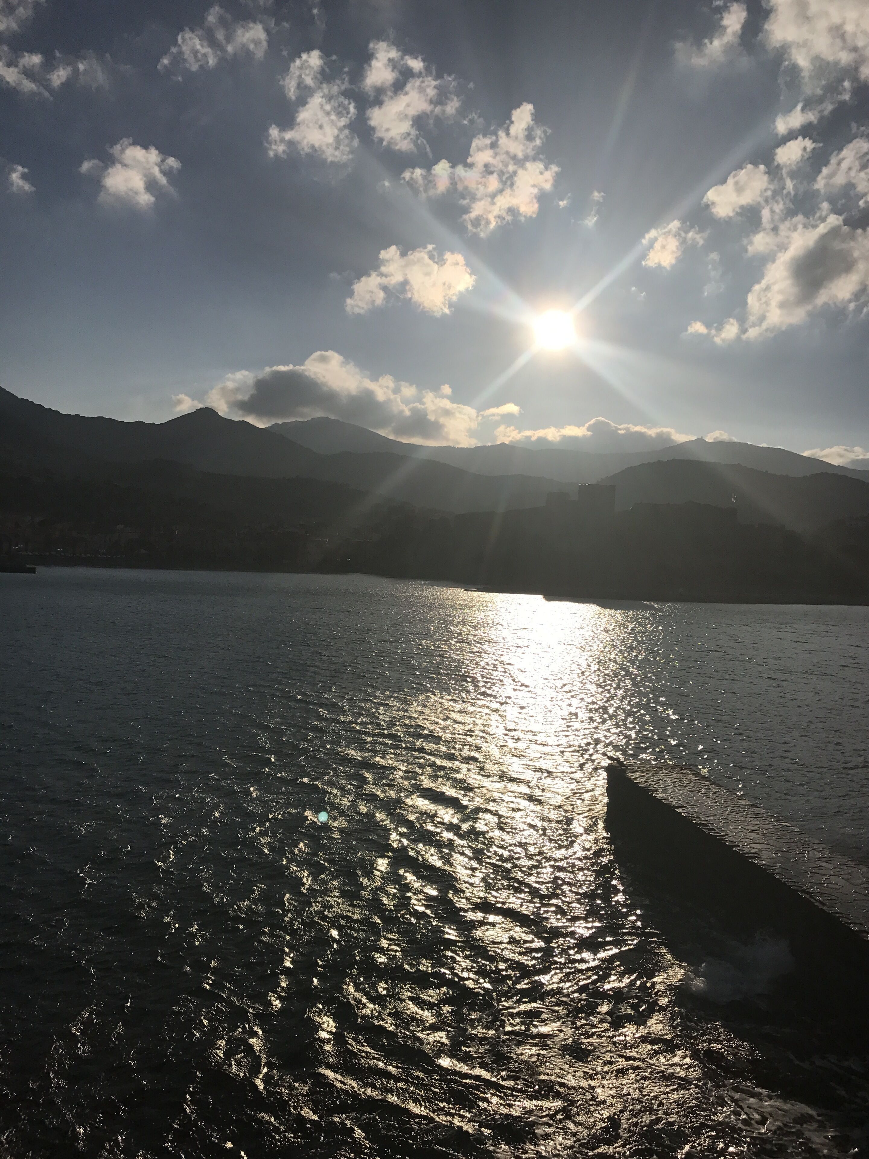 A body of water reflecting sunlight with mountains in the background.