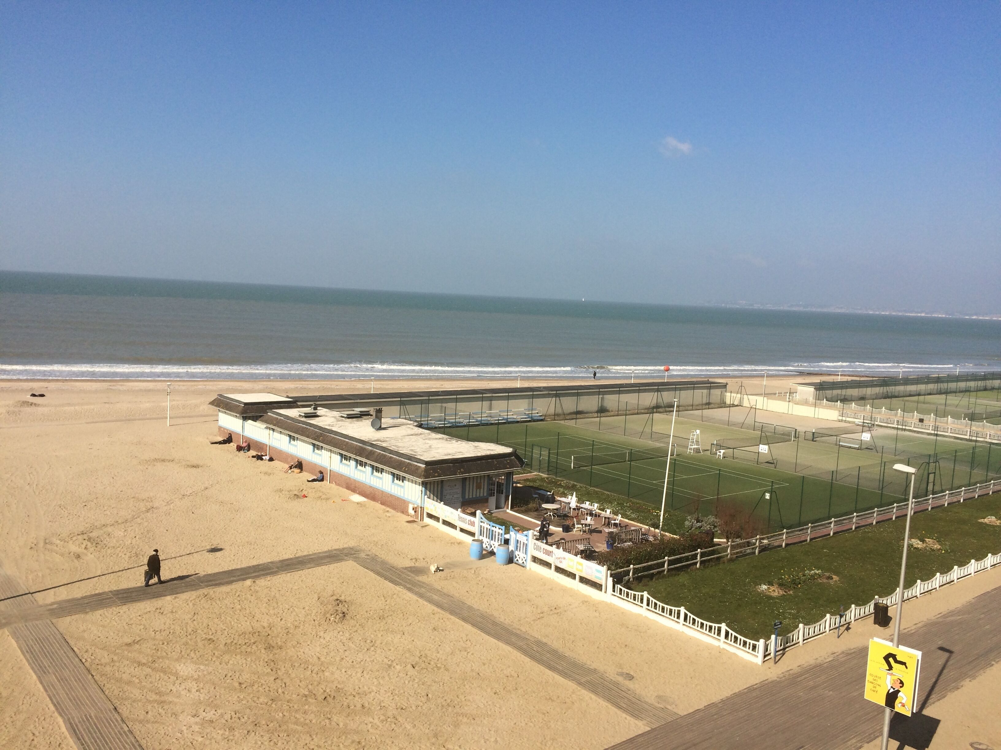 A beachside tennis court with a view of the ocean.