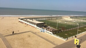 A beachside tennis court with a view of the ocean. - Trouville-sur-mer feet in the water (Trouville-Sur-Mer)