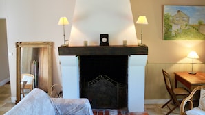 A cozy room with a fireplace, two lamps, a painting, and a mirror.
