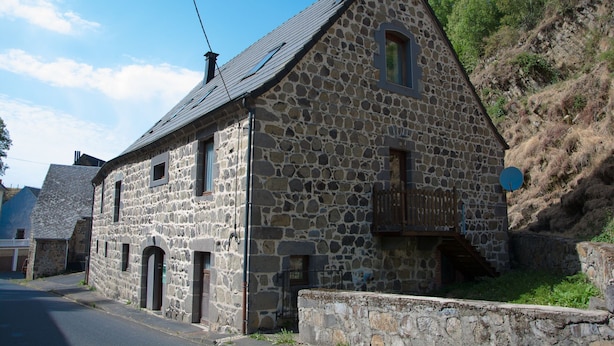 Un edificio de piedra con techo inclinado, varias ventanas y un pequeño balcón.