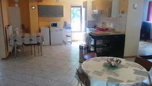 Cocina con microondas, cafetera y lavabo. Hay una zona de comedor con una mesa y sillas.