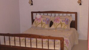Een slaapkamer met een houten bedframe, bloemenbeddengoed en twee wandlampen.