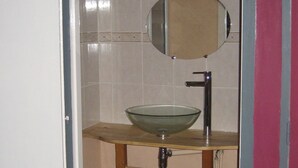 Een badkamer met een glazen wasbak, een spiegel en een houten wastafelmeubel.