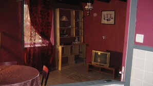 Een kamer met een houten kast, een televisie, een eettafel en een kamerbreed tapijt.