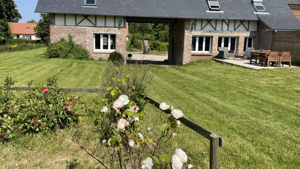 Ein großes Haus mit dunklem Dach, Backsteinmauern und einer Veranda.