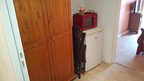 Cuina compacta amb un armari de fusta, un refrigerador blanc i un microones vermell.