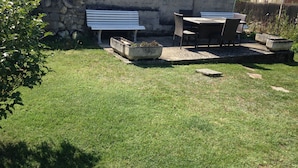 A small outdoor seating area with a bench and chairs, surrounded by a stone wall and a grassy lawn. - Rental on Amboise (Amboise)