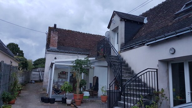 A residential property with a covered patio, potted plants, and a staircase leading to an upper level. - Rental on Amboise (Amboise)