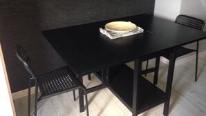 A small, dark-colored room with a black table and two black chairs. A white bowl is placed on the table. - Rental on Amboise (Amboise)