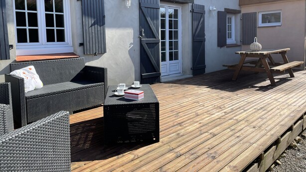 A covered outdoor seating area with wicker furniture and a picnic table.
