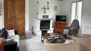A living room with a fireplace, a television, and a large wooden door.