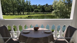 A table set for two with a view of a golf course and pond.