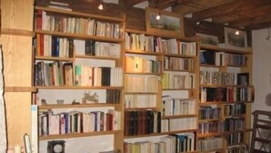 A room with multiple wooden bookshelves filled with books. There is a wooden cabinet with a clock and a small table with a lamp. - Longueville Castle, the Thines Malarce valley on Thines (Malarce-Sur-La-Thines)