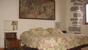 A bedroom with a bed, two bedside tables, a painting, and a stone wall. - Longueville Castle, the Thines Malarce valley on Thines (Malarce-Sur-La-Thines)