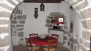 A stone-walled dining area with a red table and chairs, a clock, and a small window with a view. - Longueville Castle, the Thines Malarce valley on Thines (Malarce-Sur-La-Thines)