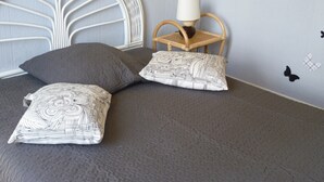 A bed with two patterned pillows, a white headboard, a wooden chair with a lamp, and butterfly decals on the wall. - Apartment 1 to 2 people in Cayeux-sur-mer in the Baie de Somme (Cayeux-Sur-Mer)