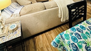 Uma sala de estar com sofá, televisão, estante amarela e tapete estampado.