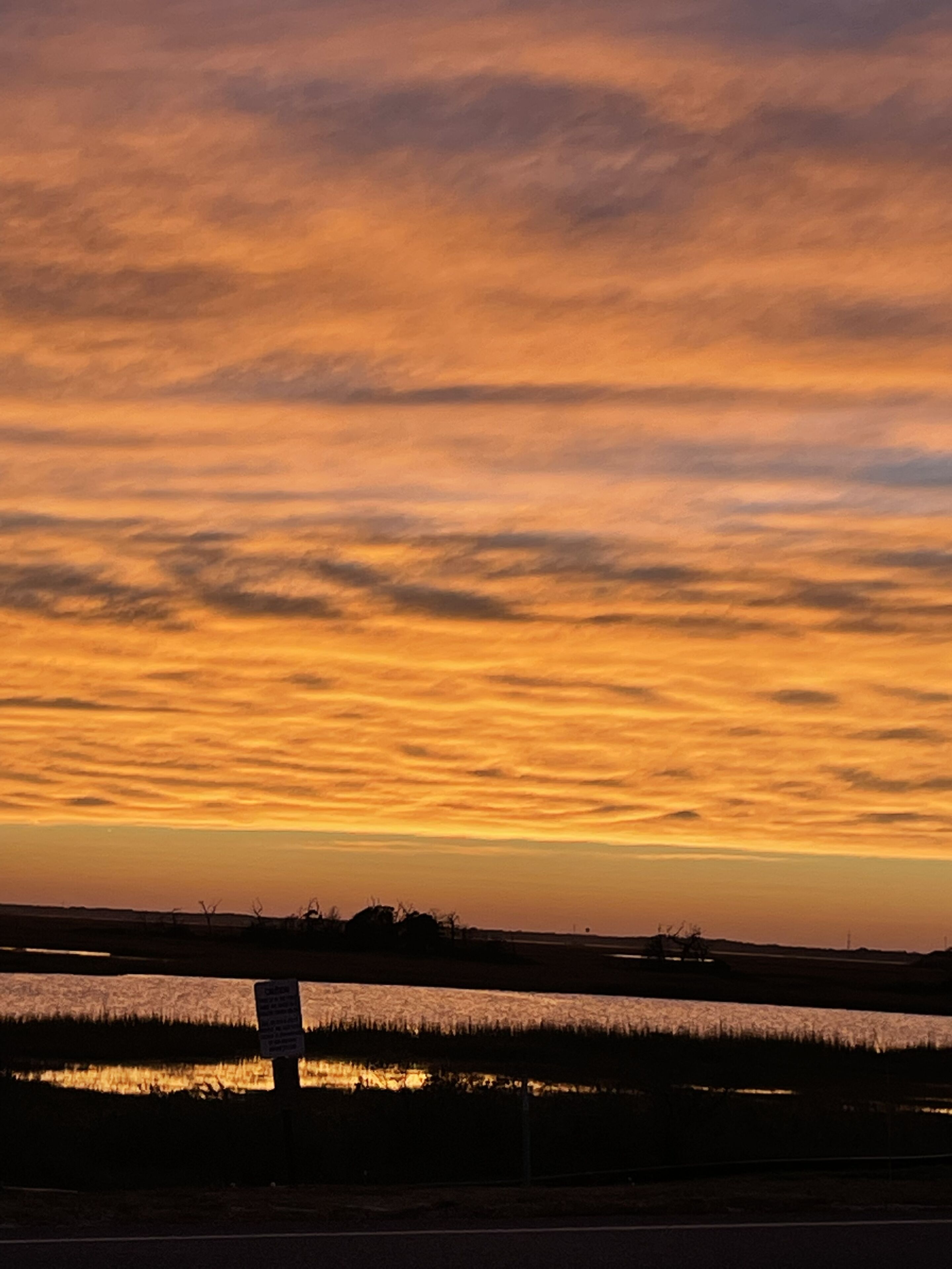 Un atardecer sobre una llanura con una señal en primer plano.