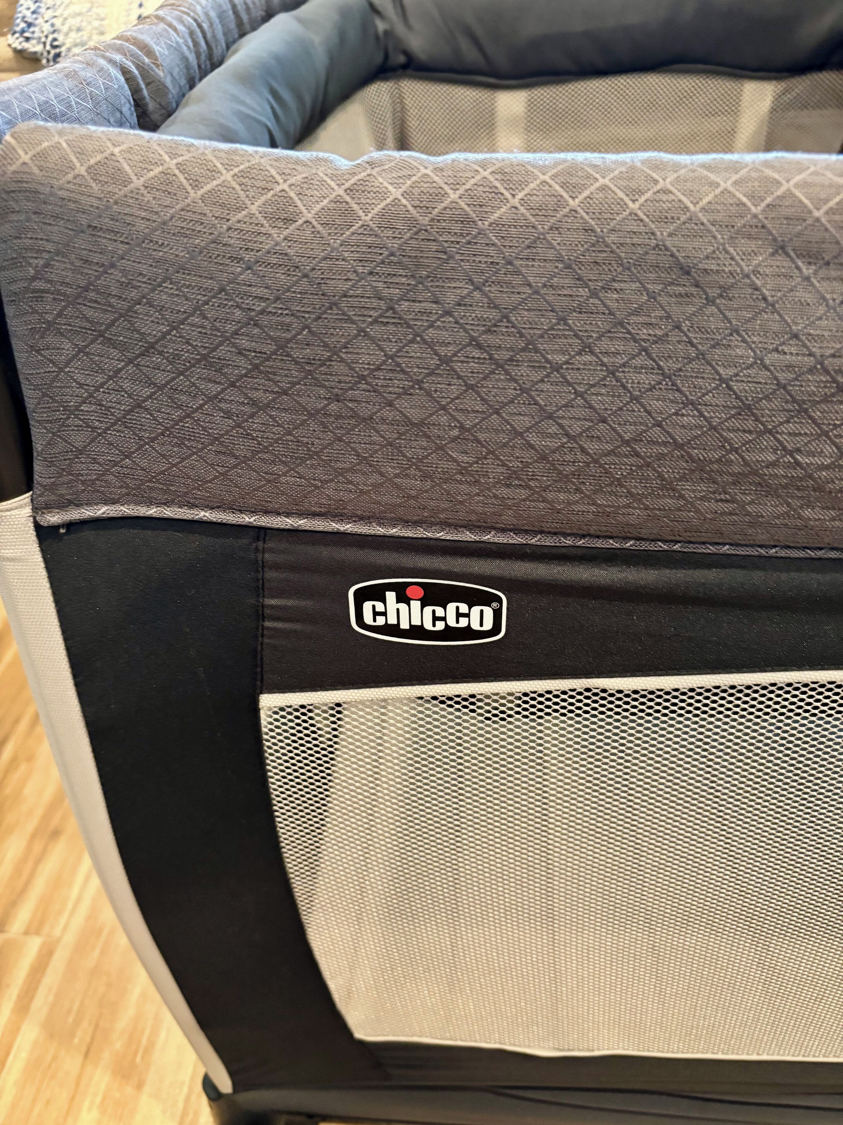 Un cuscino di un divano con motivo trapuntato e il logo 'Chicco' sul tessuto.