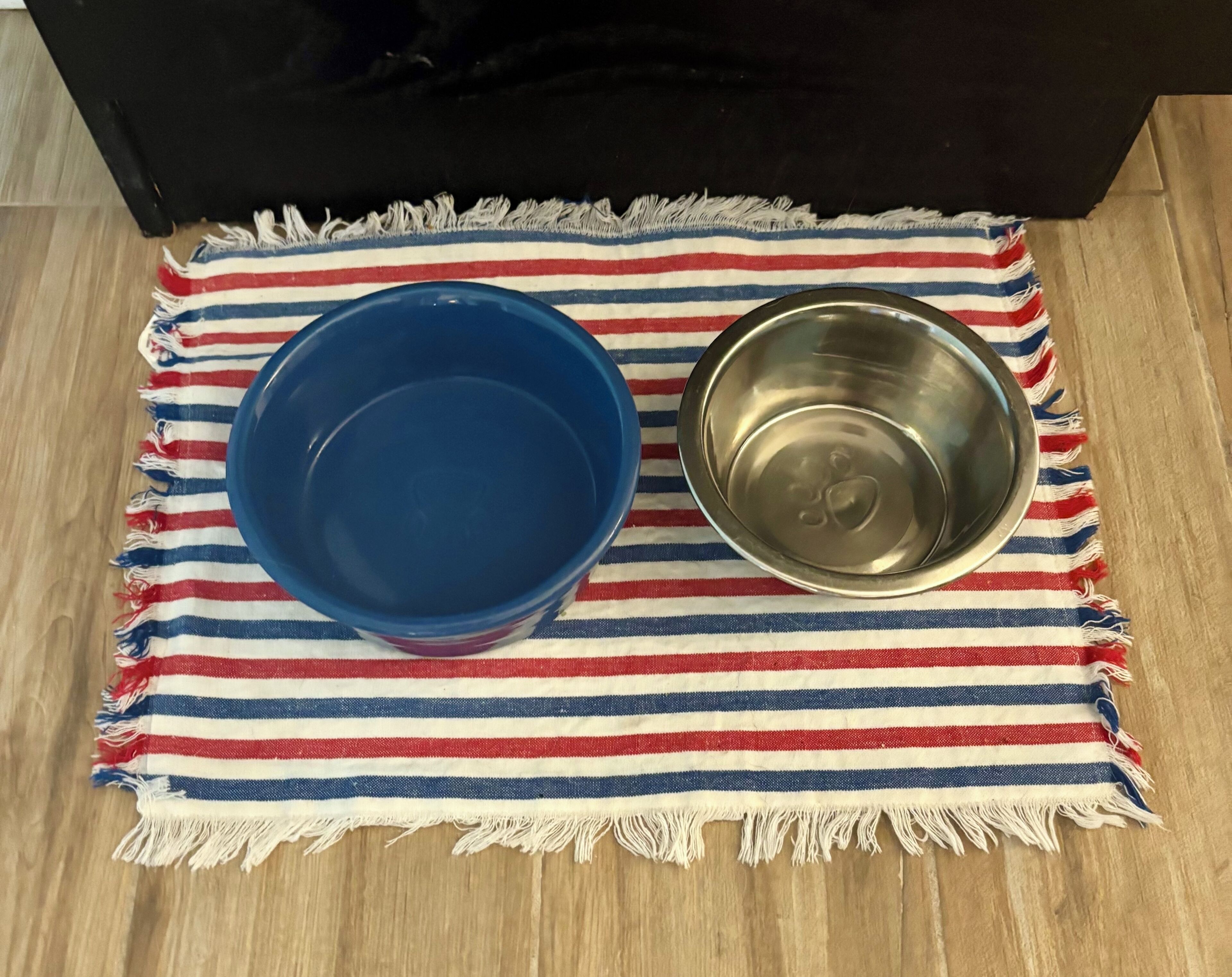 A blue bowl and a stainless steel bowl on a striped cloth.