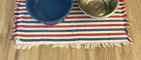A blue bowl and a stainless steel bowl on a striped cloth.
